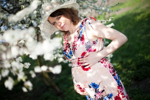 Young beautiful pregnant woman, blooming garden