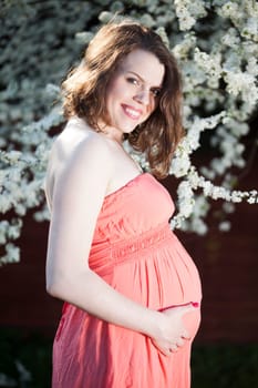 Beautiful pregnant woman relaxing outside in the Orchard