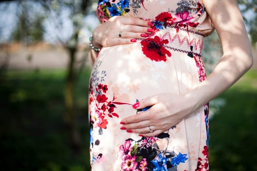 Young beautiful pregnant woman, blooming garden