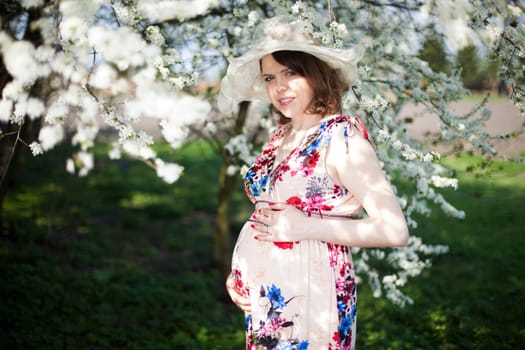Beautiful pregnant woman relaxing outside in the Orchard