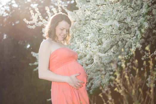 Young beautiful pregnant woman, blooming garden