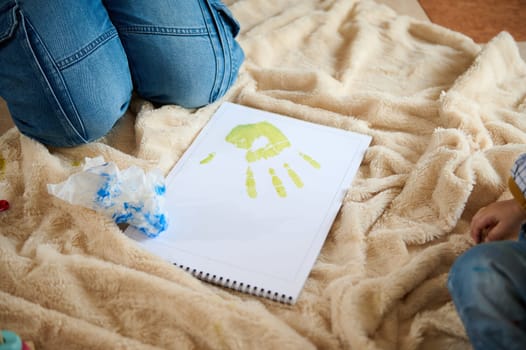 A cozy scene capturing the joy of a child painting handprints on paper, symbolizing creativity, innocence, and warm familial moments shared among loved ones.