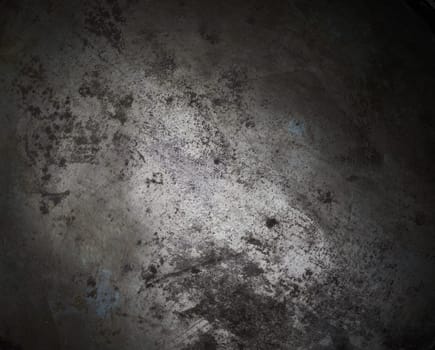 Background texture of blackened burnt metal on a vintage or rustic kitchen utensil with vignette and central highlight for copy space