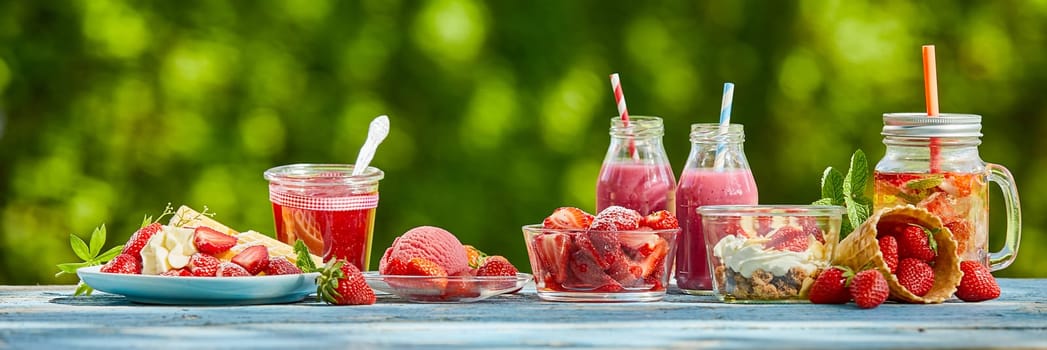 Fresh, healthy summer berry smoothie food and juices on a bright outdoor table setting in a panoramic aspect ratio.