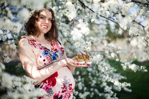 Young beautiful pregnant woman, blooming garden