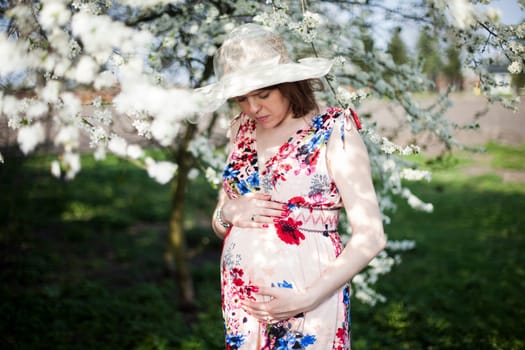 Beautiful pregnant woman relaxing outside in the Orchard