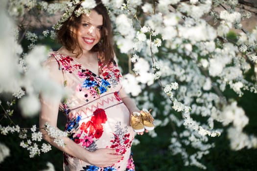 Young beautiful pregnant woman, blooming garden