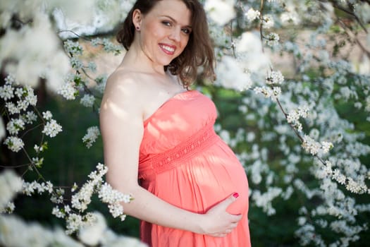Beautiful pregnant woman relaxing outside in the Orchard