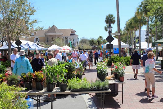 The Villages, FL, USA -April 1, 2017: People shop at an outdoor street market. People shopping at farmers market on Paddock Square streets. Farmers market shoppers buy at outdoor shops on a sunny day.
