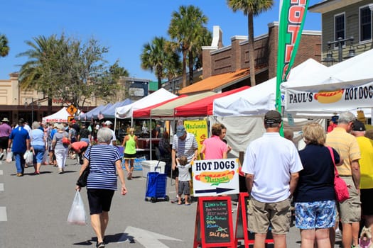 The Villages, FL, USA -April 1, 2017: Various food vendors at a farmer’s market. People lined up at the street market near Paddock Square. People shop many farmer’s market stands on a sunny day