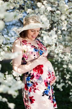 Young beautiful pregnant woman, blooming garden