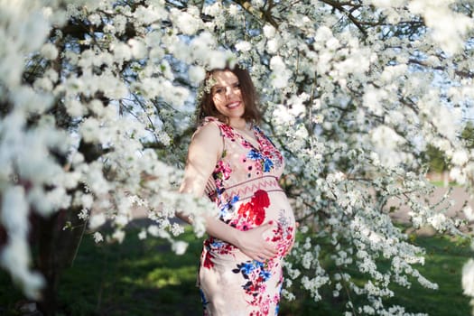 Young beautiful pregnant woman, blooming garden