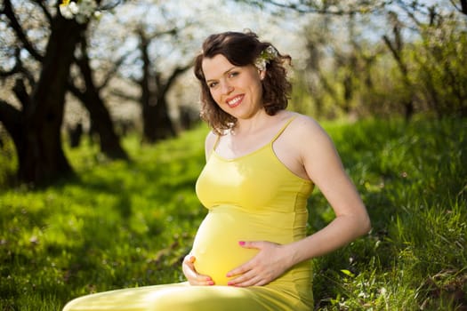 Beautiful pregnant woman relaxing outside in the Orchard