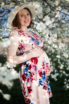 Young beautiful pregnant woman, blooming garden