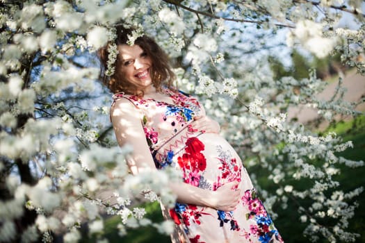 Beautiful pregnant woman relaxing outside in the Orchard