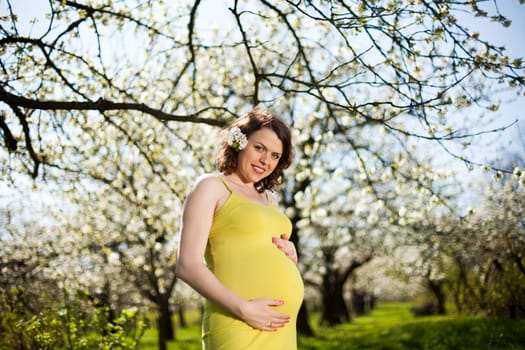 Beautiful pregnant woman relaxing outside in the Orchard