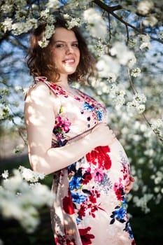 Young beautiful pregnant woman, blooming garden