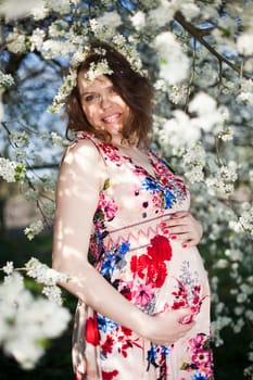 Young beautiful pregnant woman, blooming garden