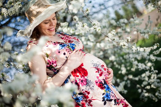 Beautiful pregnant woman relaxing outside in the Orchard