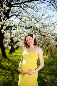 Beautiful pregnant woman relaxing outside in the Orchard
