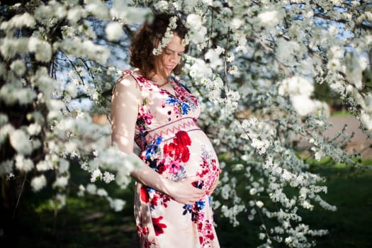 Young beautiful pregnant woman, blooming garden