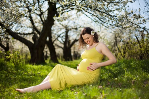 Beautiful pregnant woman relaxing outside in the Orchard