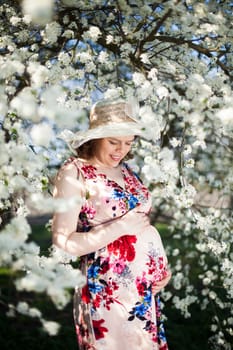 Beautiful pregnant woman relaxing outside in the Orchard