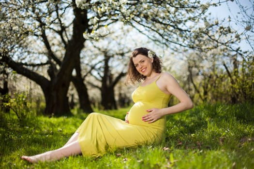 Beautiful pregnant woman relaxing outside in the Orchard