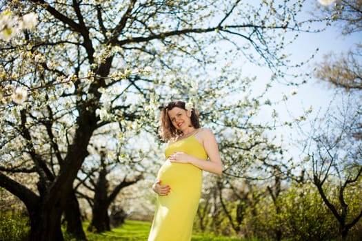 Beautiful pregnant woman relaxing outside in the Orchard