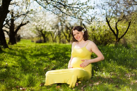 Beautiful pregnant woman relaxing outside in the Orchard