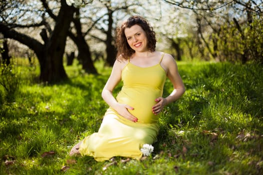 Beautiful pregnant woman relaxing outside in the Orchard