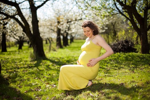 Beautiful pregnant woman relaxing outside in the Orchard