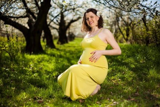 Beautiful pregnant woman relaxing outside in the Orchard
