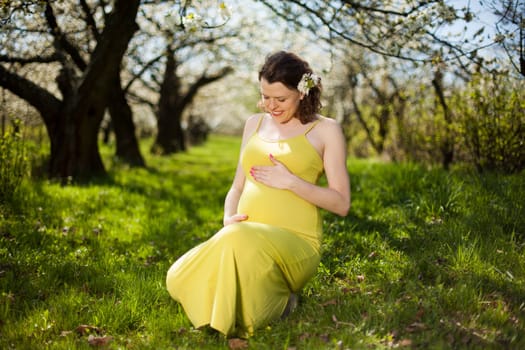 Beautiful pregnant woman relaxing outside in the Orchard