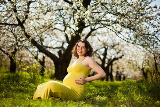 Beautiful pregnant woman relaxing outside in the Orchard