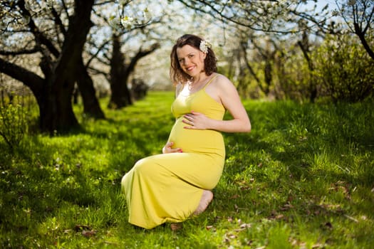 Beautiful pregnant woman relaxing outside in the Orchard