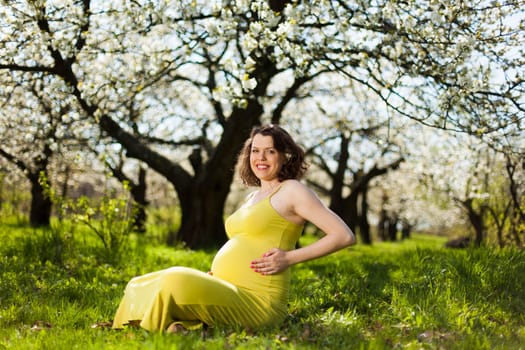Beautiful pregnant woman relaxing outside in the Orchard