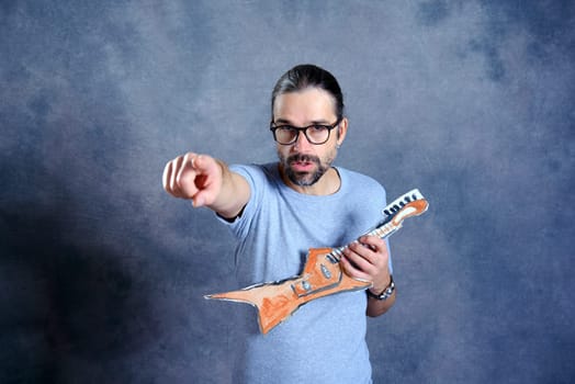 wild young man with cardboard guitar in front of gray background