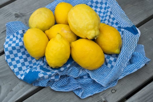 yellow lemons with blue towel on wooden ground