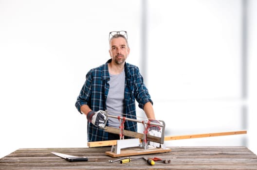 worker in blue plaid  shirt sawing wood