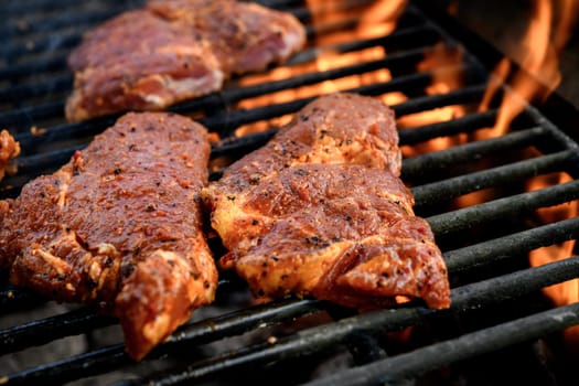 grilled pork with flames on charcoal barbecue