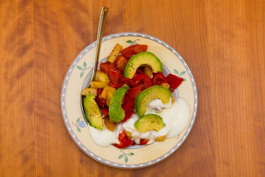 plate with fried vegetables and row avocado on wooden ground