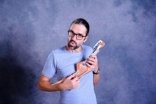 wild young man with cardboard guitar in front of gray background