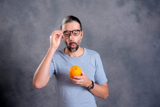 long haired young man with orange in front of gray background