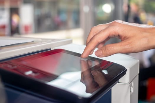 Woman's hand working on the copier's touchscreen in a copy center