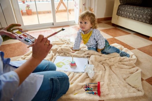 A joyful moment showing a child and parent painting together at home, enjoying quality time and engaging in creative activities. Perfect representation of family moments and emotional connection.
