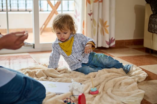 A young child explores creativity inside a family home, engaging in painting activities and emotional bonding with their parent in a nurturing environment.