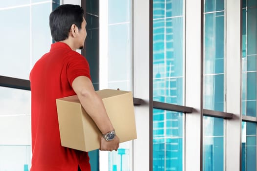 Back view of asian male courier holding the parcel on the office