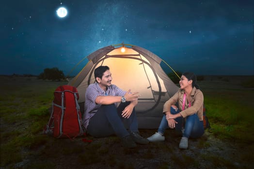 Attractive asian couple relaxing in front of the tent at night