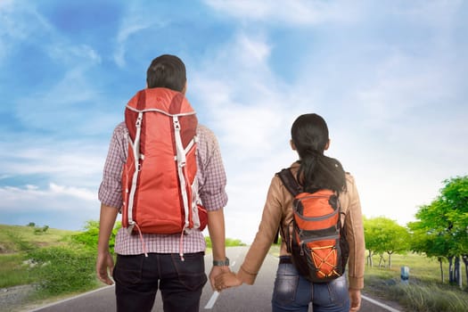 Romantic asian tourist couple holding hands and walking with blue sky background